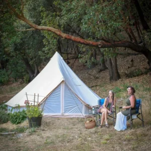 Guests relaxing outside a bell tent in the morning