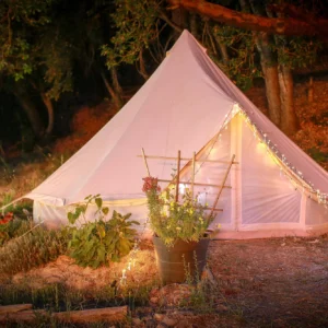 White bell tent with string lights in a garden