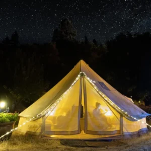 Lit bell tent at night beside the trees