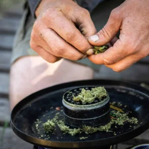 Hands breaking up cannabis over a grinder