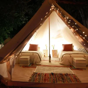 Bell tent with string lights and two beds at night