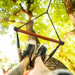 Feet on a rope swing hanging in a sunlit oak tree