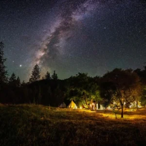 Glamping tents lit up under a starry night sky