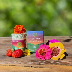 Cannabis products on a wooden table with fresh flowers and strawberries