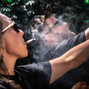 Woman exhaling smoke beside a cannabis plant